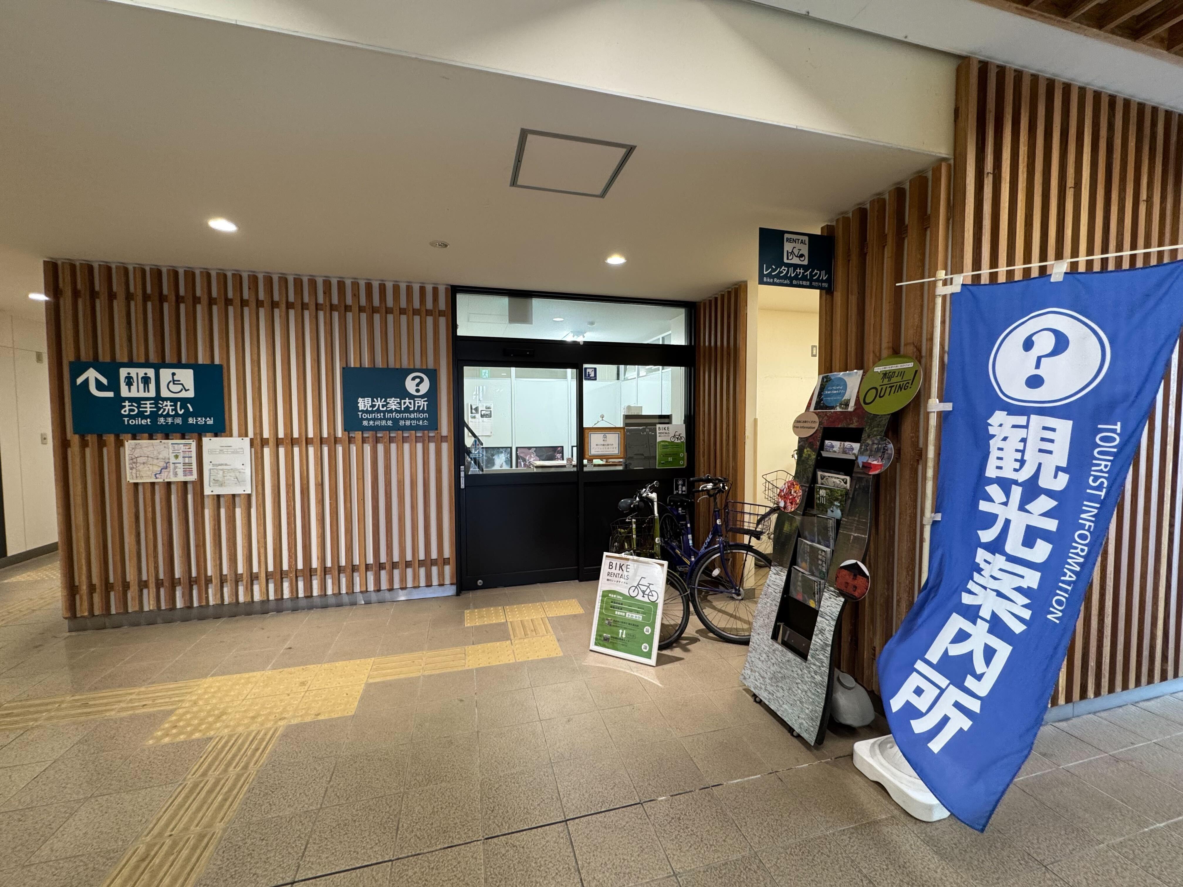 柳川市観光案内所の入口。多言語表記の看板と青い観光案内用の旗が設置されている。